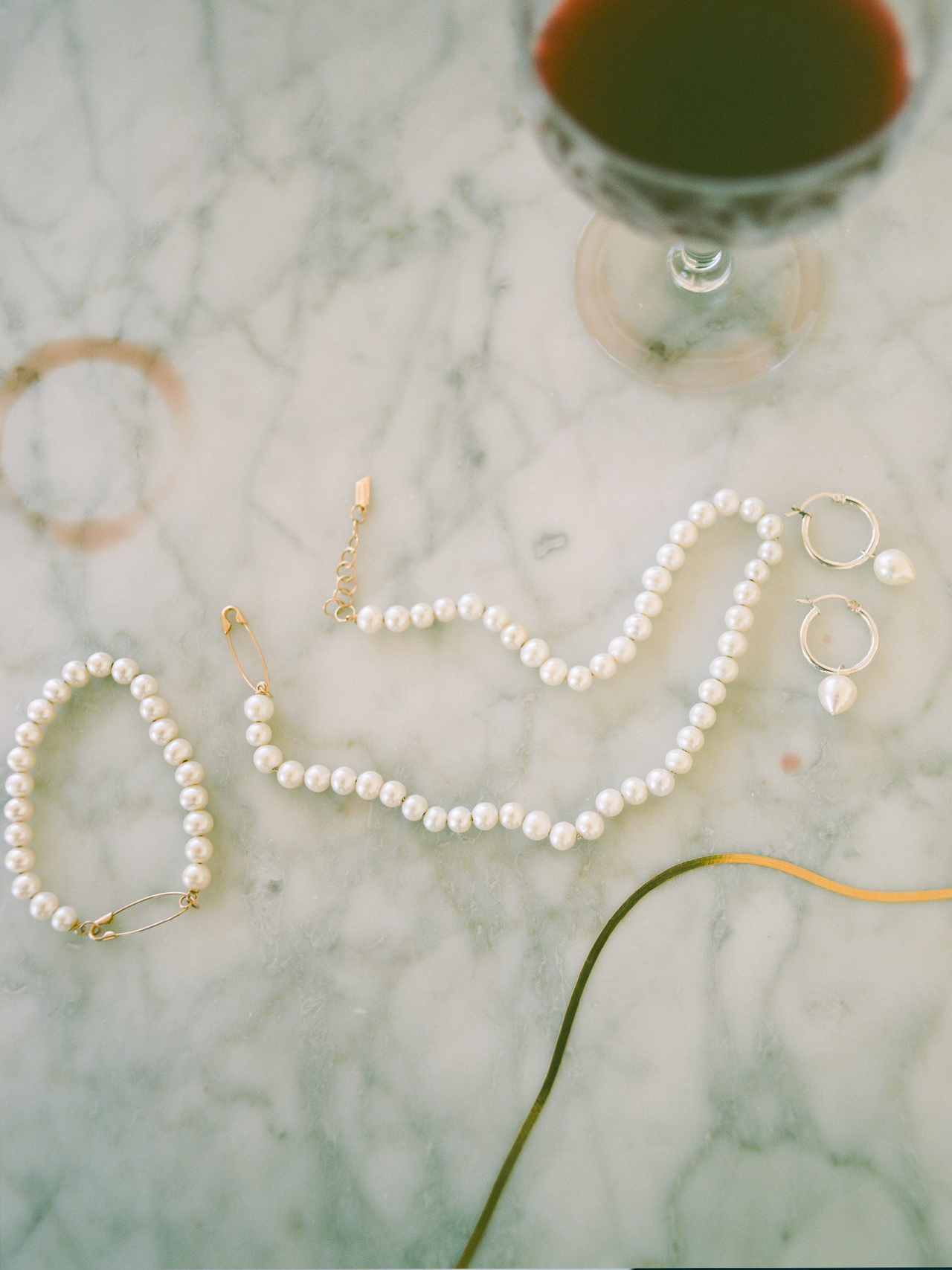 Flat lay imagery of pearl safety pin bracelet on marble backdrop