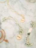 flat lay imagery of disk pendants engraved with the words "love" and "peace" in gothic writing on marble backdrop