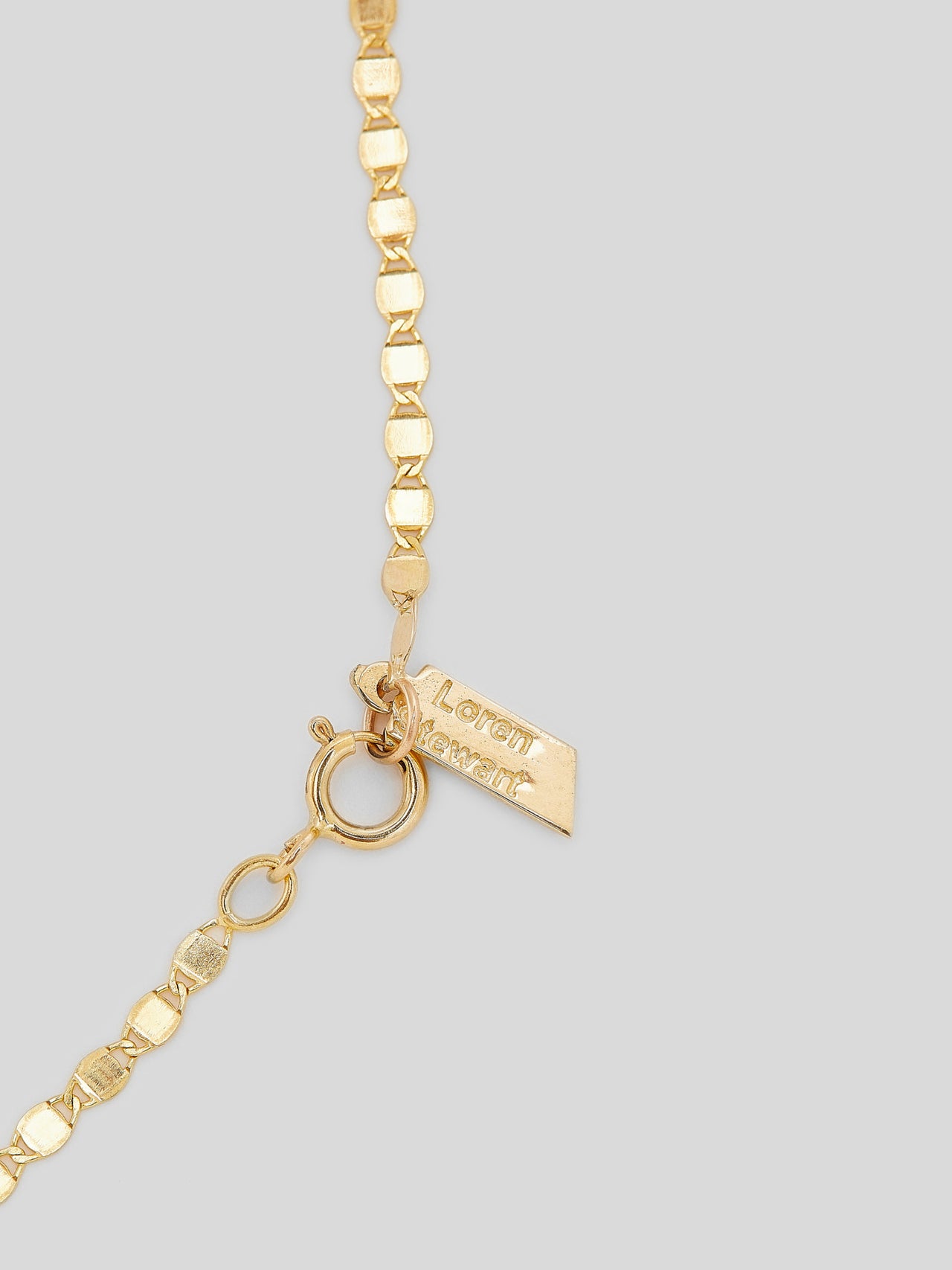 Close up of clasp and logo on Product image of 14kt yellow gold valentino chain bracelet on white background. 