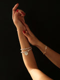 Sterling Silver Rumi Wrap Charm Bracelet pictured on models wrist. Black background. 