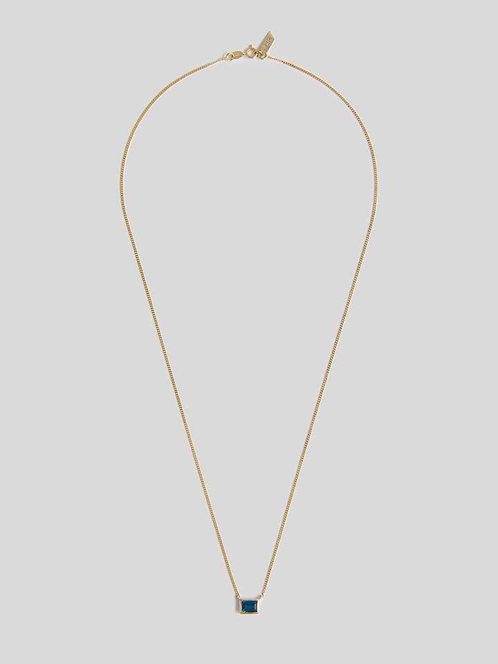 Product shot of Necklace with thin yellow gold chain and blue rectangle topaz pendant. Shot on white background.   