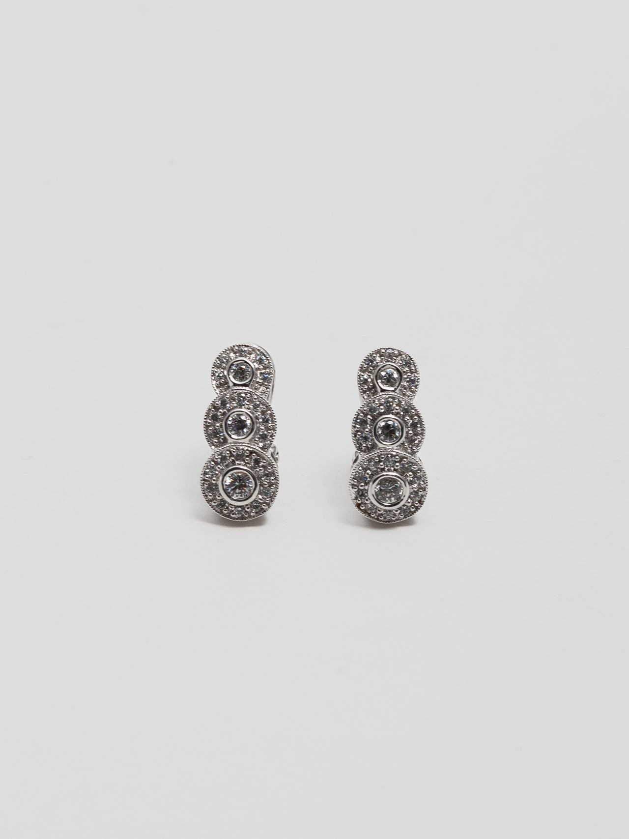 10Kt White Gold and Diamond Huggie Studs pictured on light grey background.