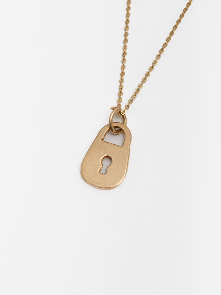 Close up picture of 14Kt Yellow Gold Padlock Charm & Chain. Light grey background. 