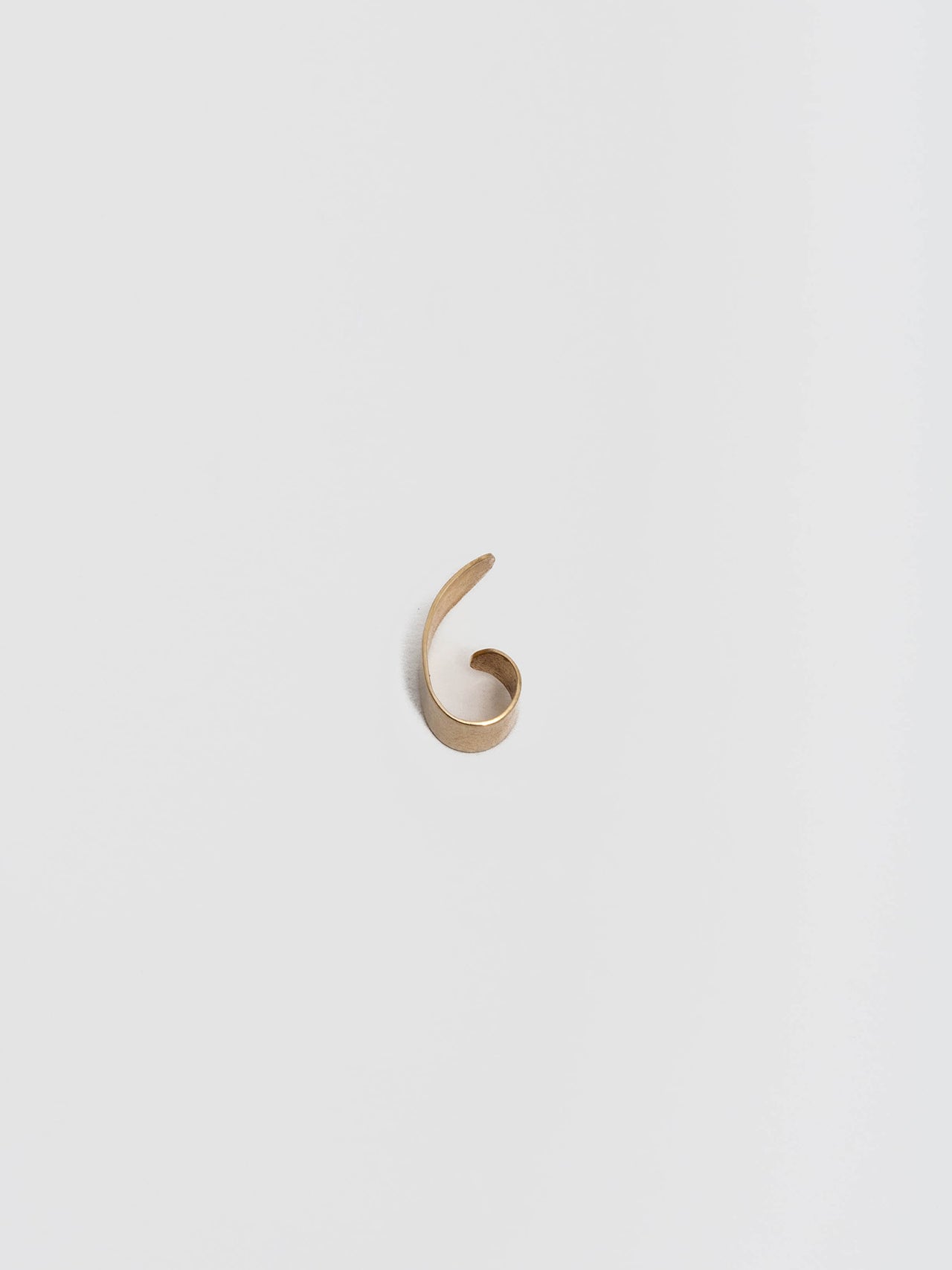 Birds eye view of 14kt Yellow Gold Ear Cuff pictured on light grey background.