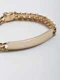 14kt Yellow Gold Solid XL Cuban Chain ID Bracelet pictured from side close up on light grey background.
