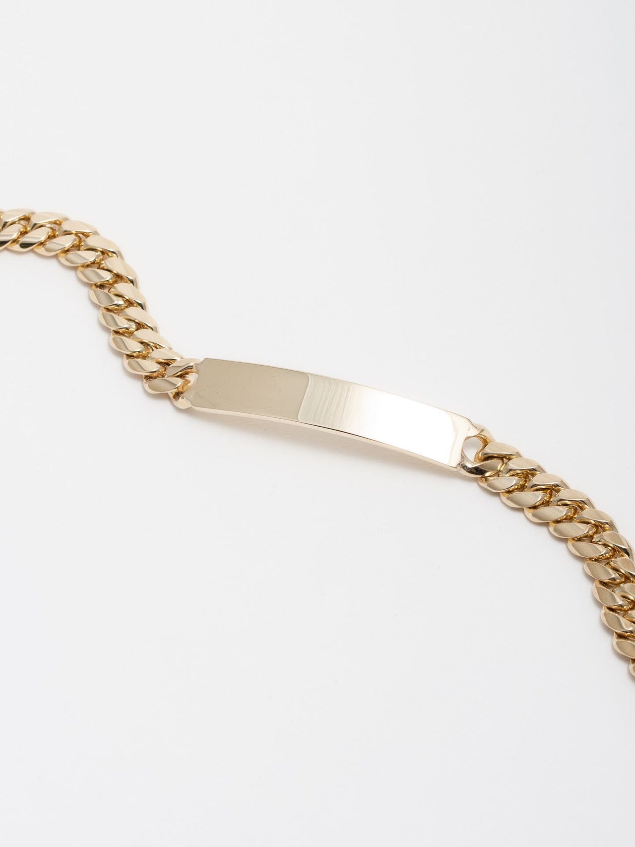 14kt Yellow Gold Solid XL Cuban Chain ID Bracelet pictured laid out length wise on light grey background.