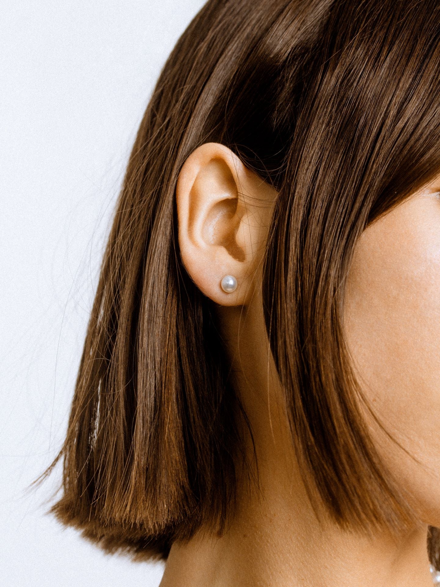 On model image of pearl studs on models ear.