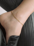 Close up of  14kt Yellow Gold XL Lightweight Havana Chain Anklet pictured on models foot. Black shoes and apparel. 