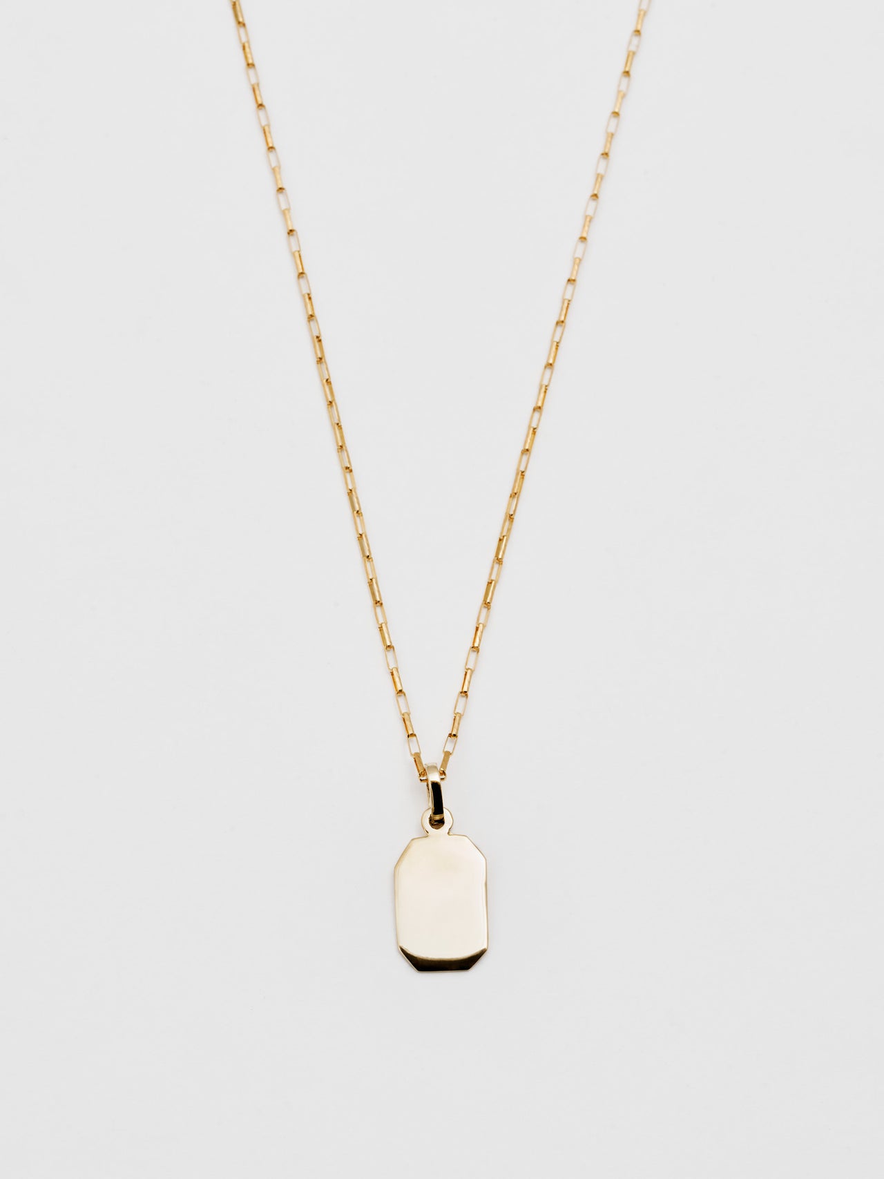 Close up of 14kt Octagonal Id Charm + Elongated Box Chain pictured on light grey background.