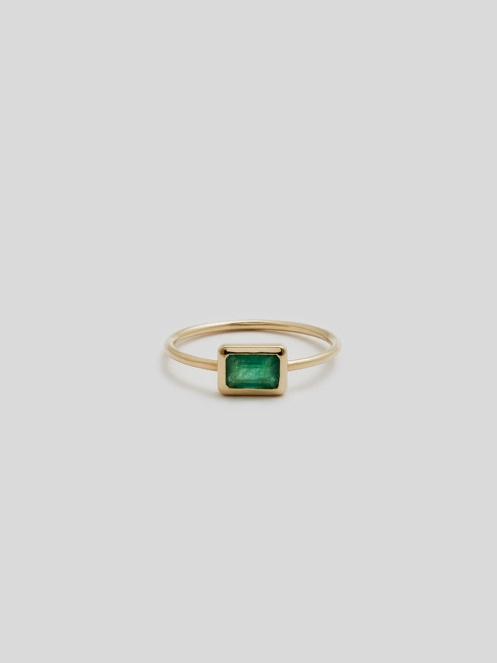 Product shot of the front of Emerald Cut Bezel Ring V.I (Shiny Thin 14Kt Yellow Gold band with rectangular Green Quartz stone framed with yellow gold). With white background. 