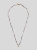 Product image of lavender pearl necklace with small yellow gold heart pendant on white background. 