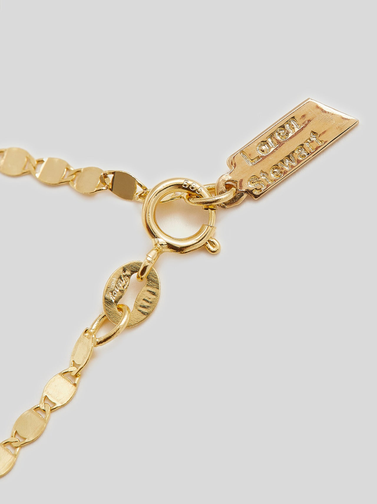 Close up of logo and clasp on Product image of yellow gold valentino chain necklace on white background. 