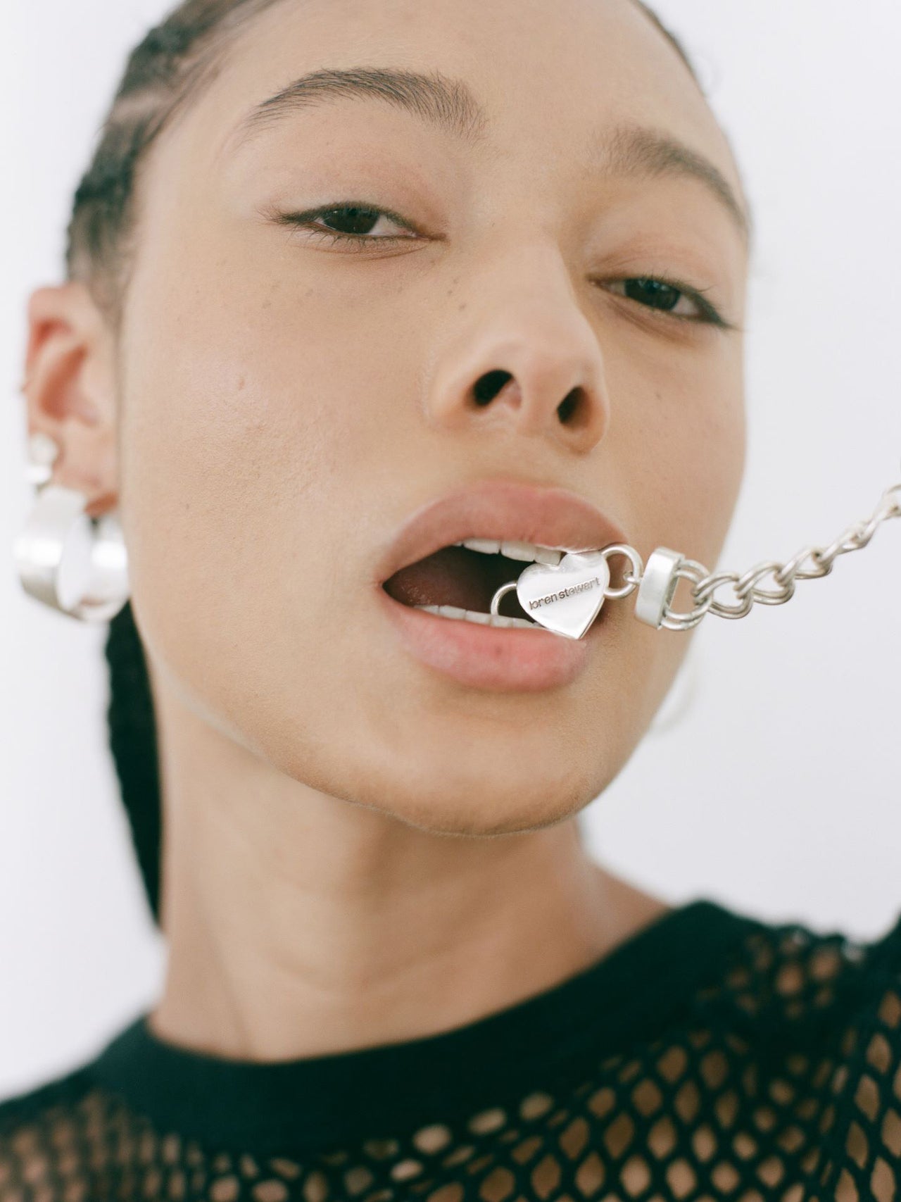 Sterling Silver Double Link Chain Necklace with Amore Heart closure pictured in models mouth. Light grey background.