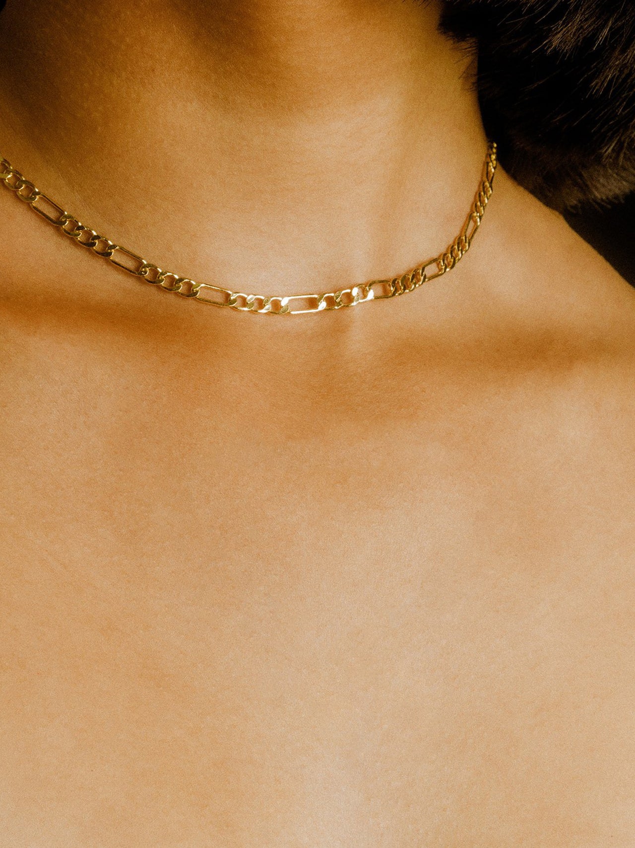14KT Yellow Gold Figaro Chain shot on models neck.