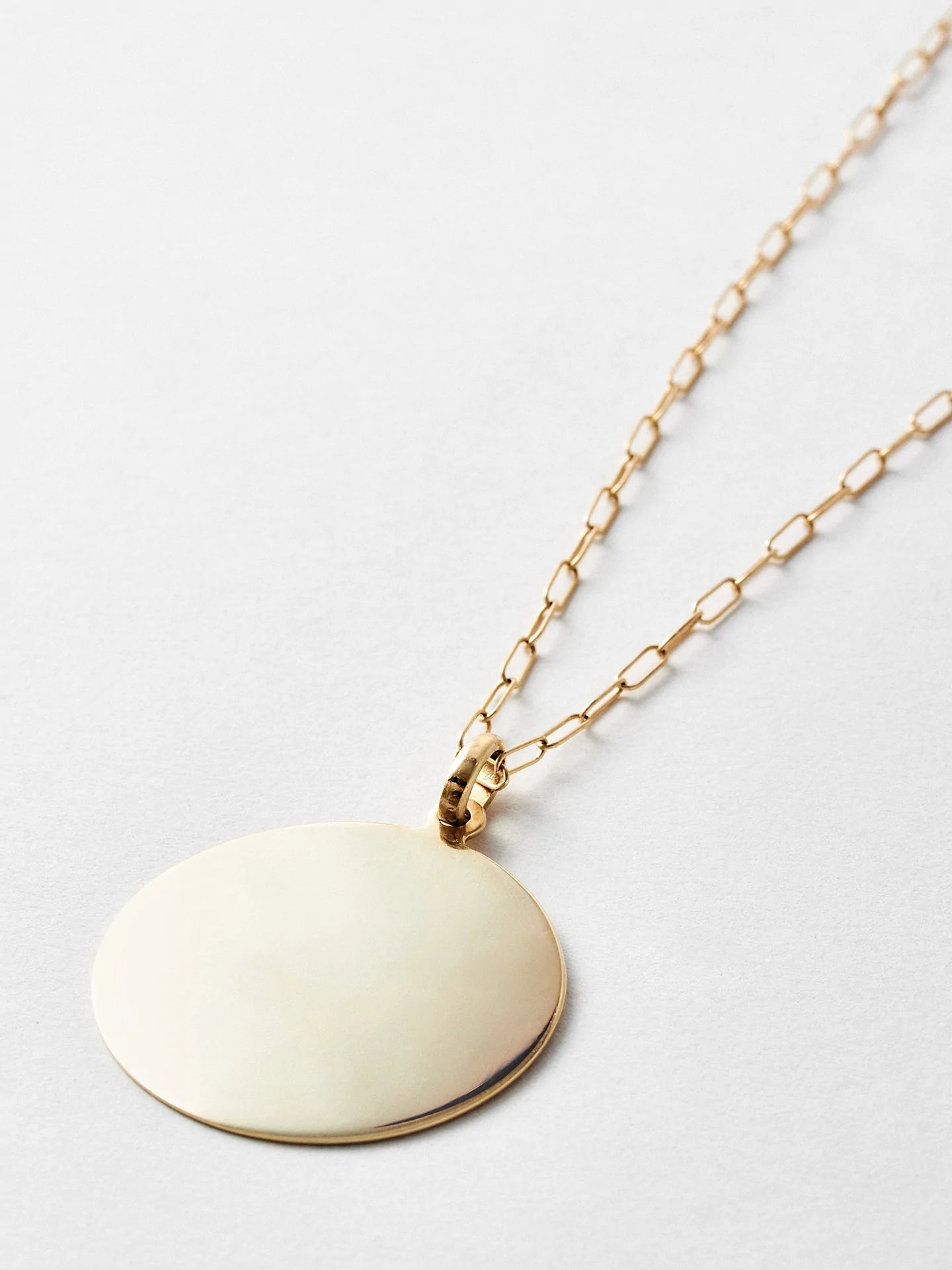 14kt Yellow Gold XL Disk Pendant, 30mm Width, shot on chain laying down. Light grey background.