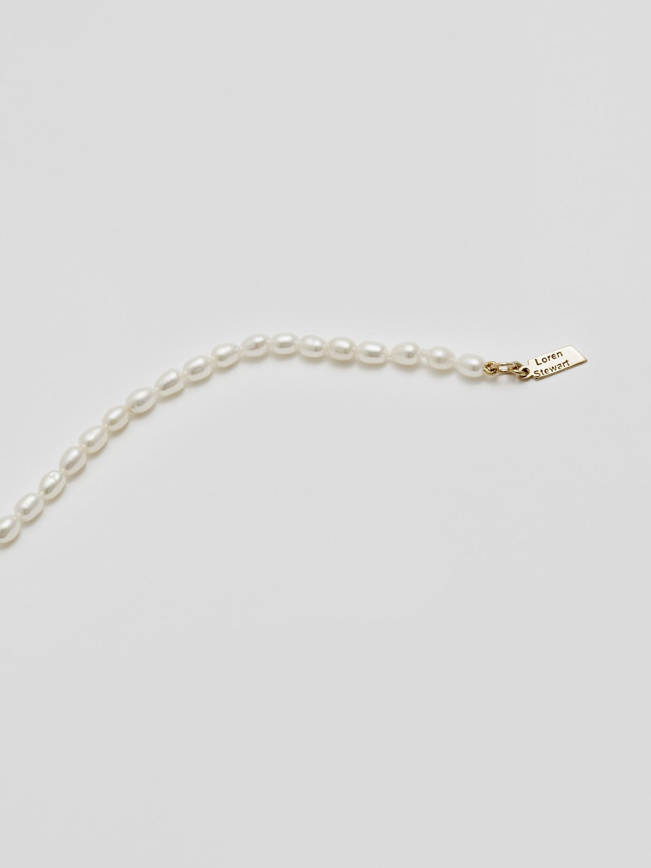 Product shot of White Rice Pearl Anklet including logo. Light grey background. 