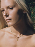 Model wearing Gem Drop Pendant (14kt Yellow Gold Pendant with yellow gemstone pendant) along with yellow gold necklace background: greenery  