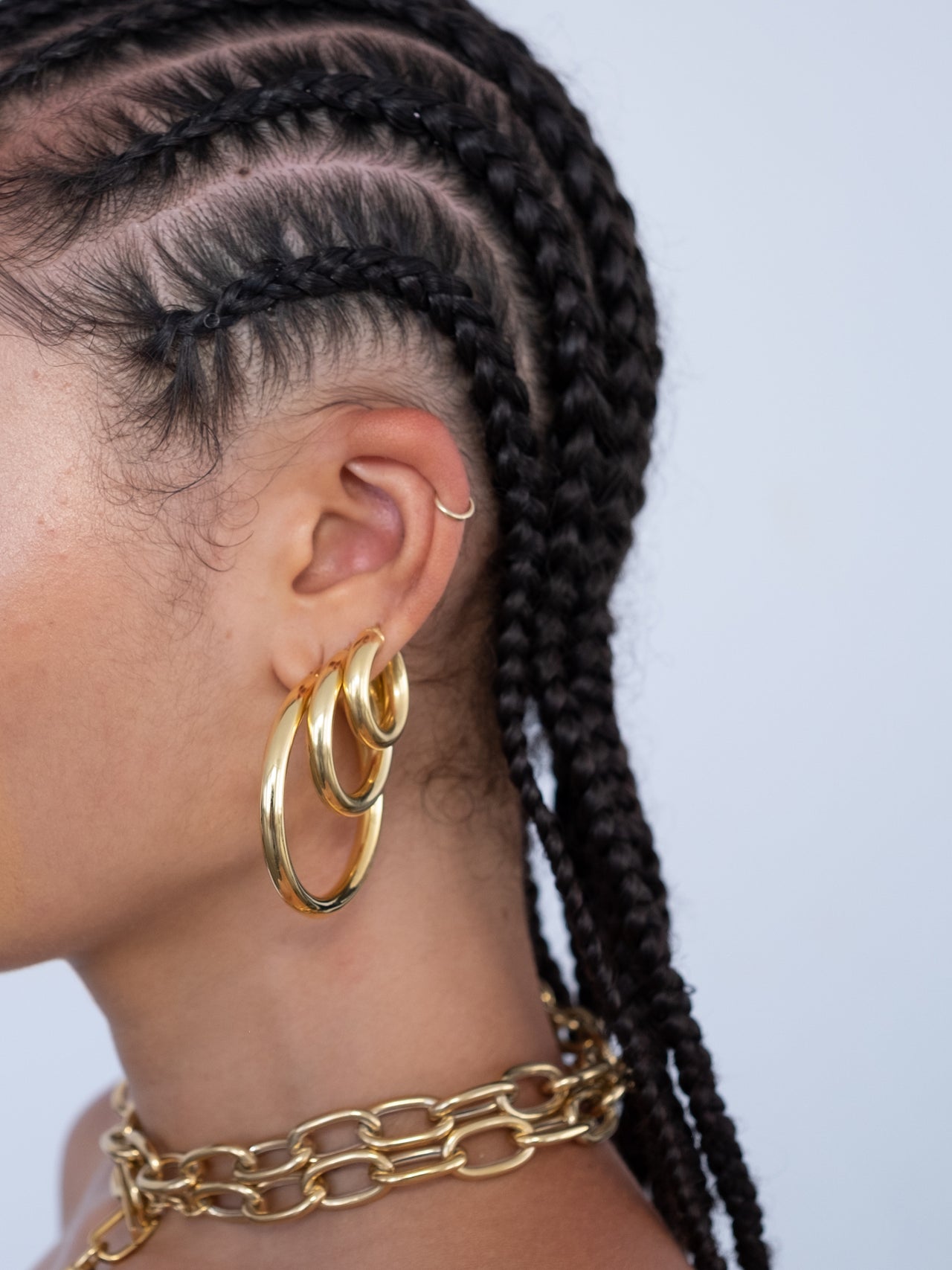 The Tru Hoops - Small, Medium and Large (Vermeil Gold) pictured on models ear. Grey backdrop