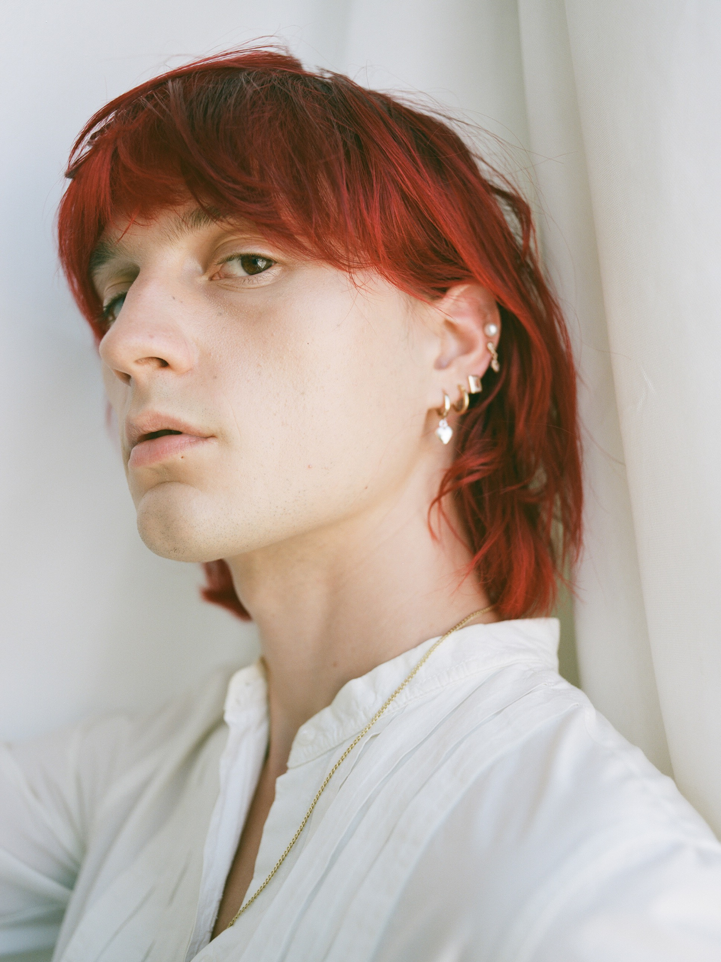 On model image of pearl studs on models ear with multiple other earrings. 