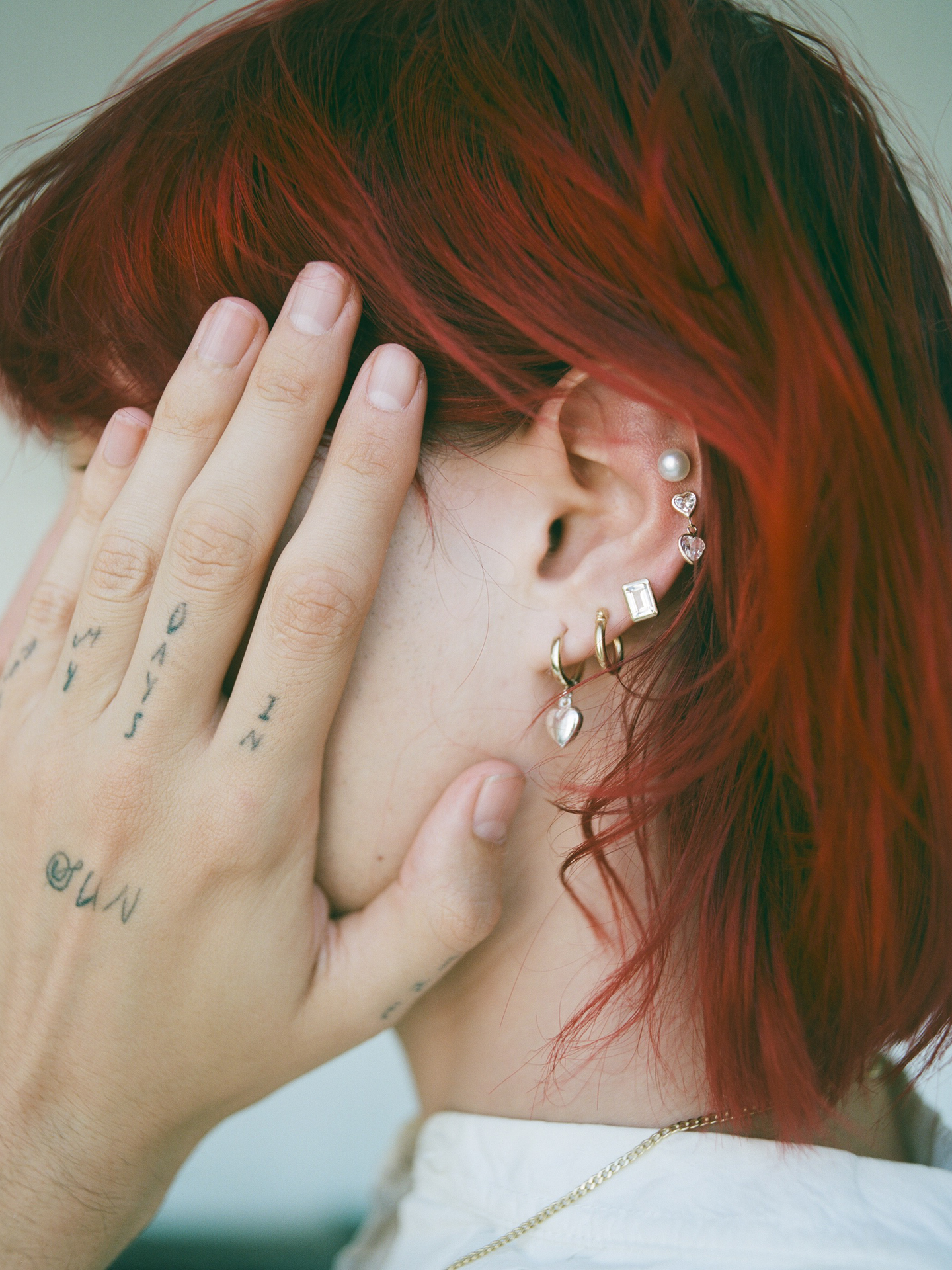 On model image of pearl studs on models ear with multiple other earrings. 