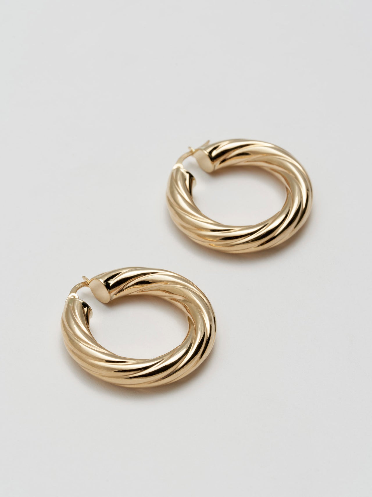 Side angle product shot of Whirlwind Hoops (14Kt Yellow Gold Hoop Earrings Diameter: 30mm Thickness: 6mm) Shoot on white background