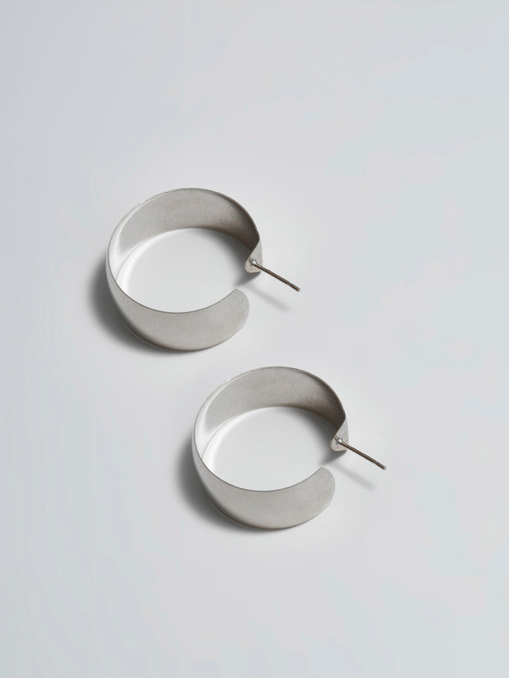 Product shot of the XL Dome Hoops(Sterling Silver Hoop Earrings 30mm Diameter 12mm Wide) Background: Grey backdrop
