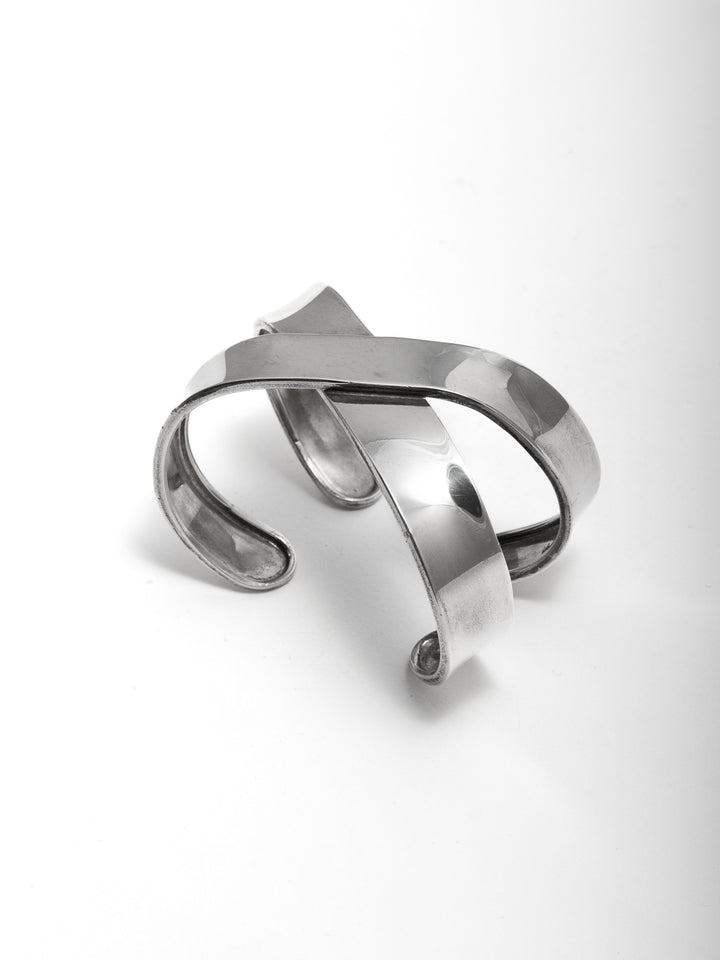 Sterling Silver X Cuff Bracelet pictured from side angel on light grey background.