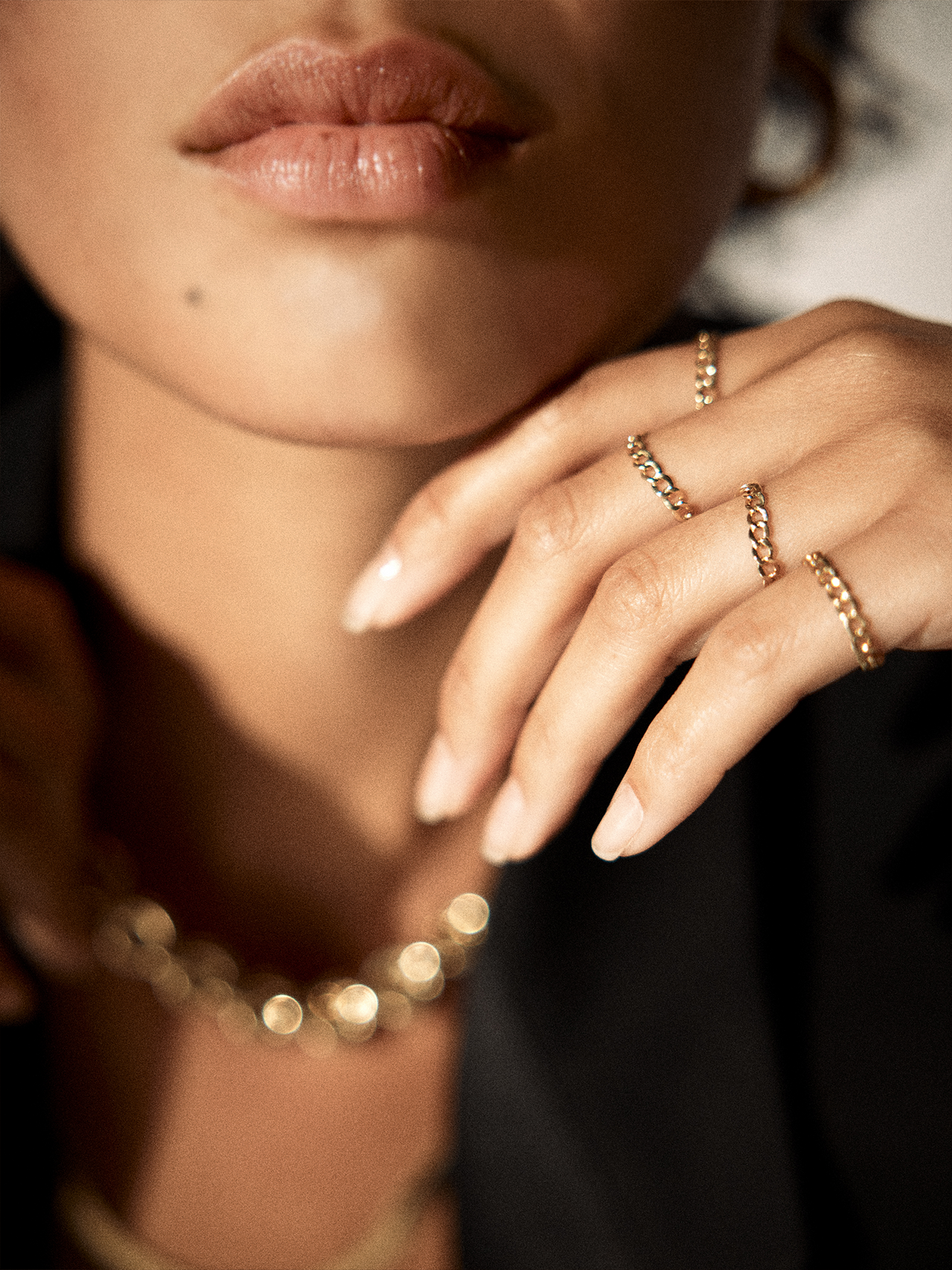 On model image wearing multiple havana chain rings on hand. 