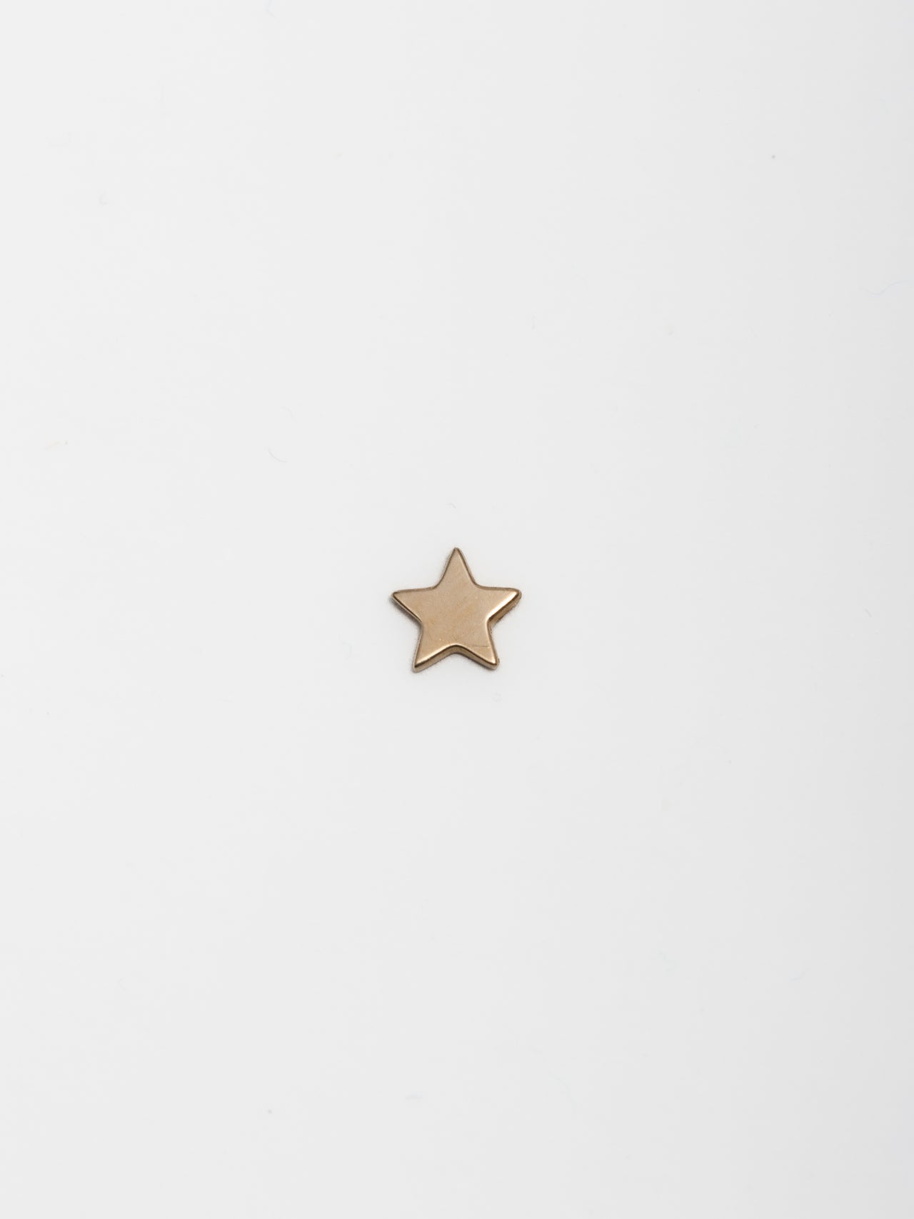 14kt Yellow Gold Mini Star Stud pictured on light grey background. 