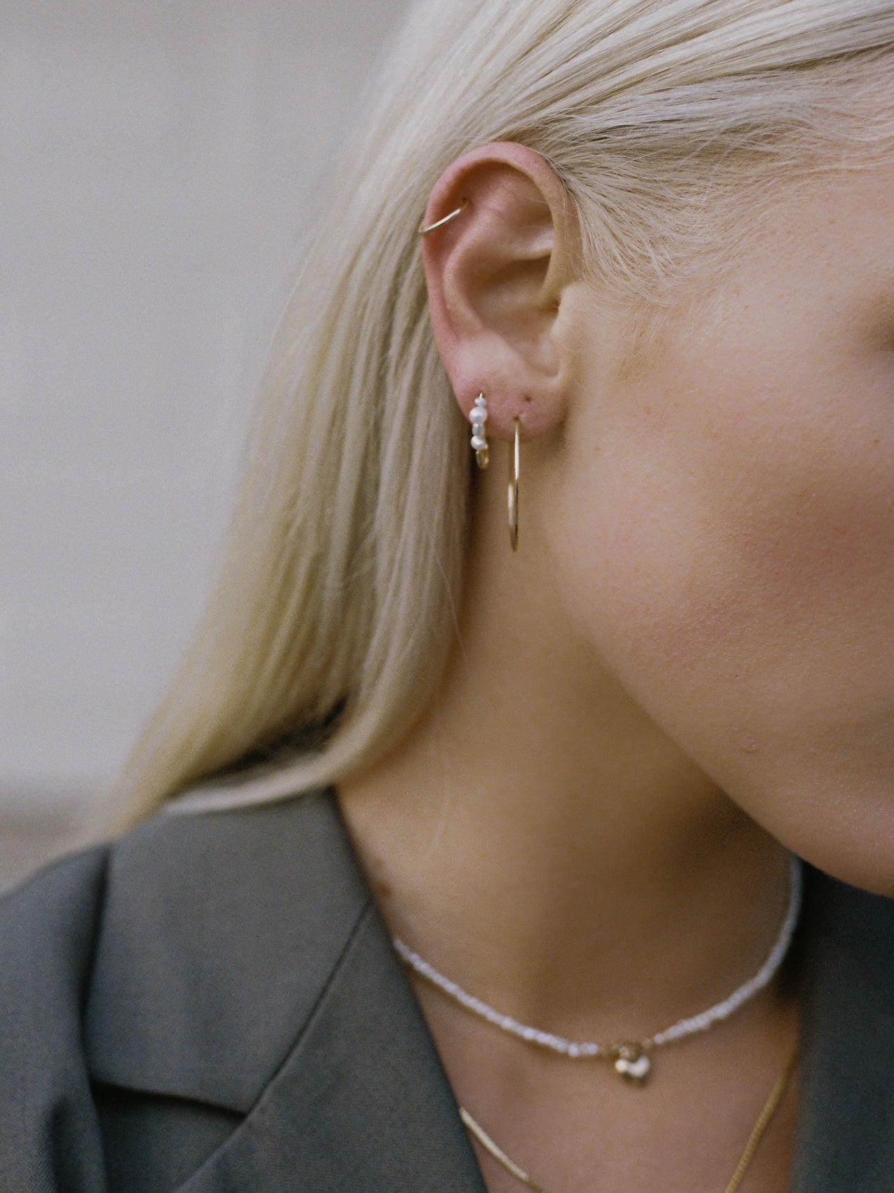 Model wearing mini mixed safety pin earring with two gold infinity hoops.