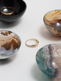 Flatlay image of natural stone catch alls with yellow gold dome ring and jade signet ring
