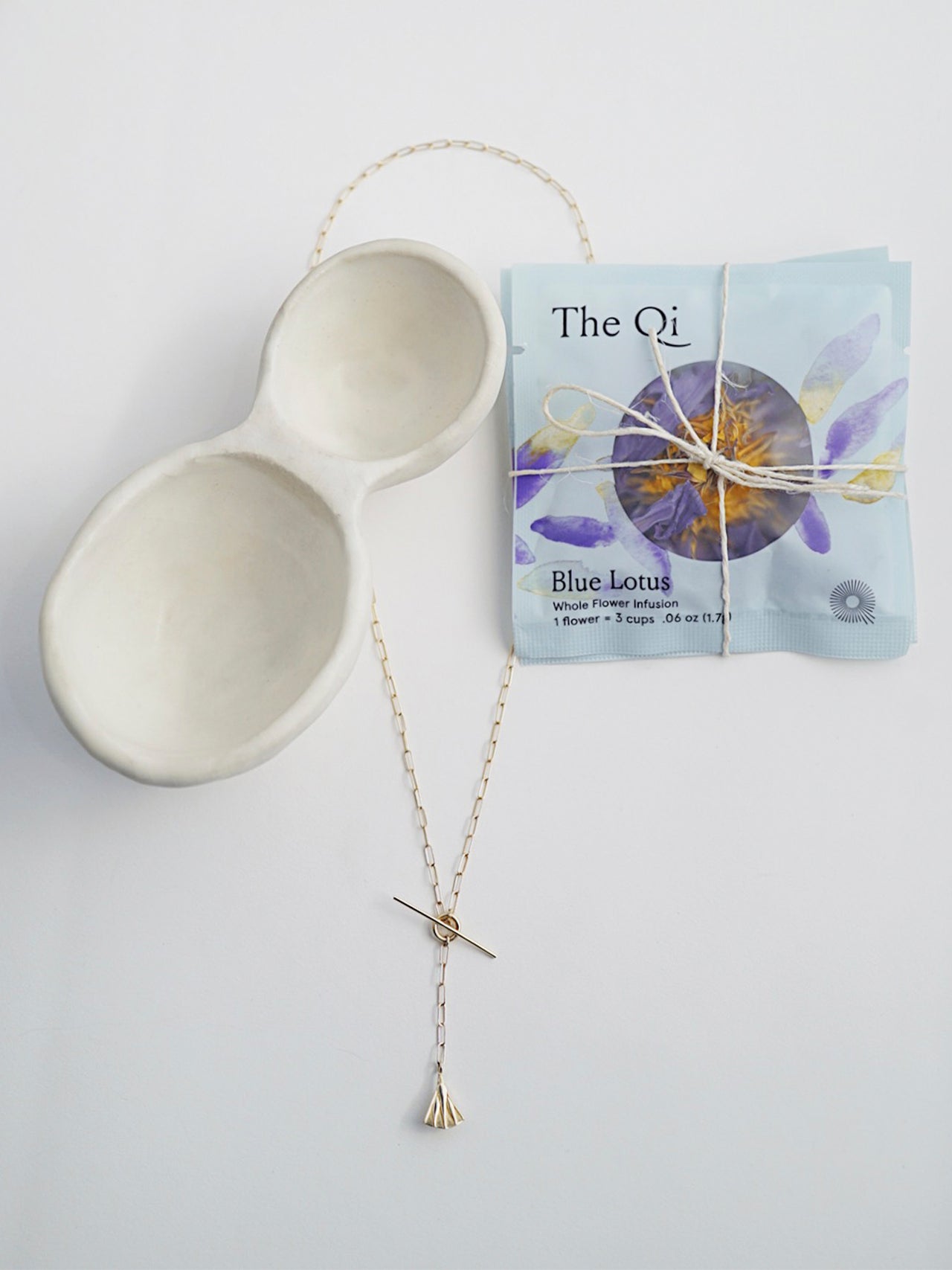 14Kt Yellow Gold Lotus Toggle Necklace with Long Link Chain layed next to Blue Lotus tea and Ceramic Catch All 
